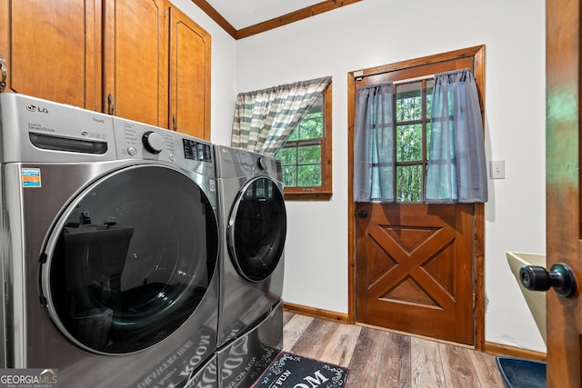 washroom with washing machine and clothes dryer, cabinet space, wood finished floors, baseboards, and ornamental molding