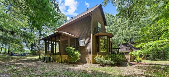 view of side of home featuring a sunroom, a wooden deck, stairway, and cooling unit