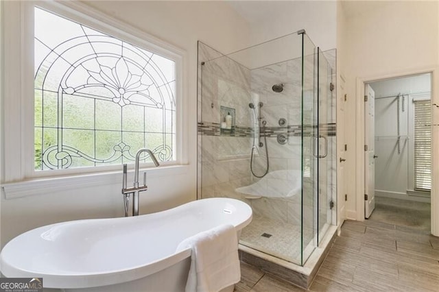 bathroom featuring a stall shower, plenty of natural light, and a freestanding tub