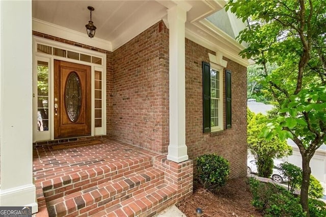 view of exterior entry featuring covered porch and brick siding