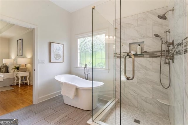 bathroom with a stall shower, a soaking tub, and wood finished floors