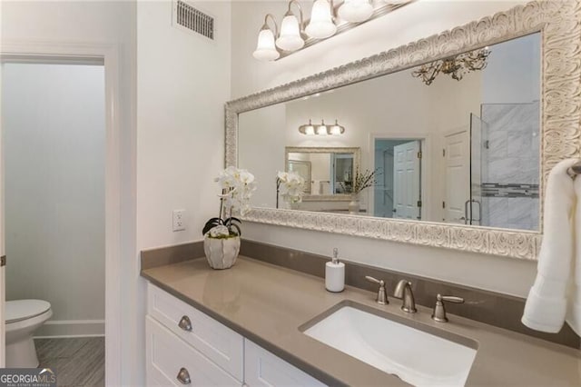 bathroom with a stall shower, vanity, toilet, and baseboards