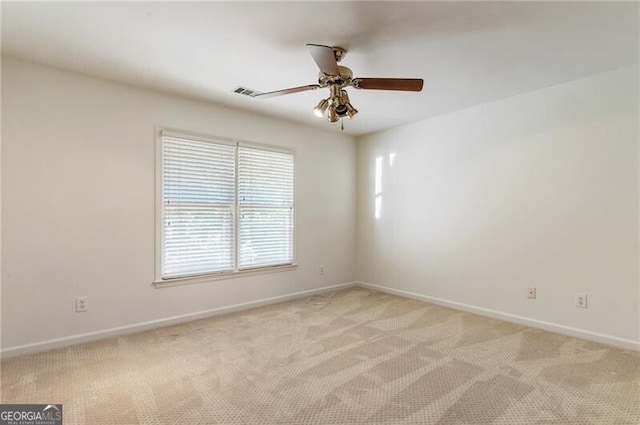 spare room featuring light colored carpet, baseboards, and ceiling fan