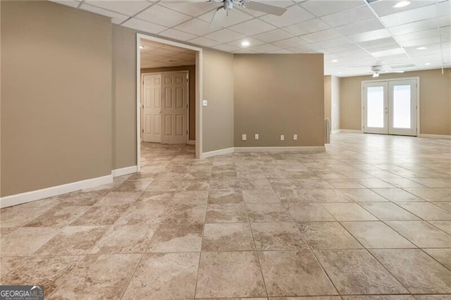 basement featuring ceiling fan, a drop ceiling, baseboards, light tile patterned flooring, and french doors