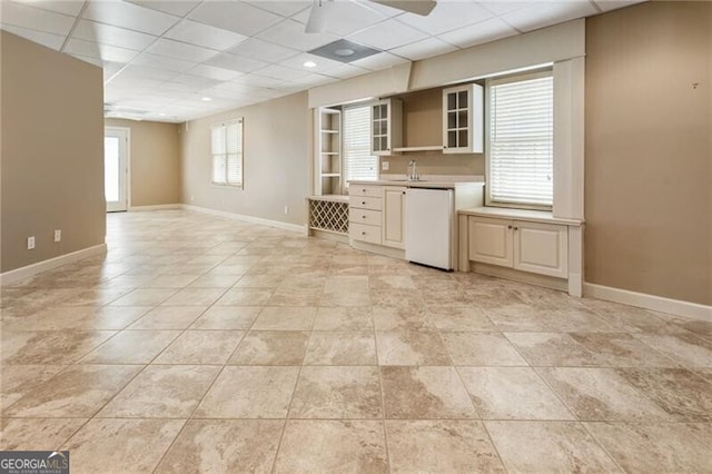 kitchen featuring fridge, a paneled ceiling, ceiling fan, baseboards, and light countertops