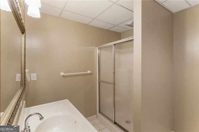 bathroom featuring a sink, a shower stall, a paneled ceiling, and tile patterned floors