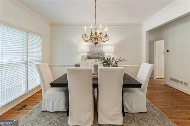 dining area featuring a chandelier, healthy amount of natural light, wood finished floors, crown molding, and baseboards