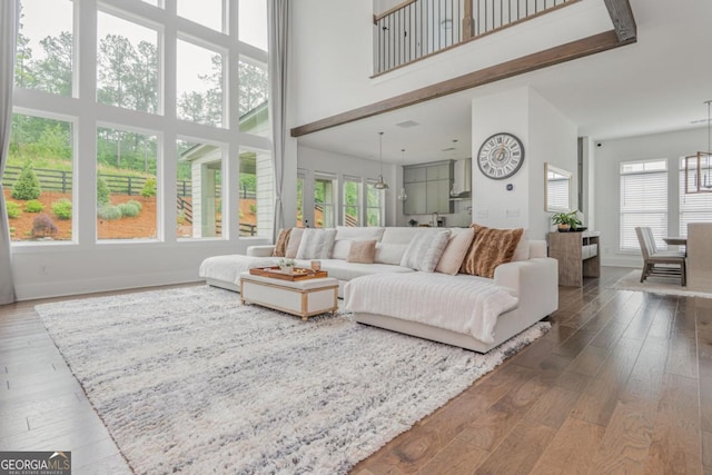 living area featuring a towering ceiling, hardwood / wood-style flooring, and baseboards