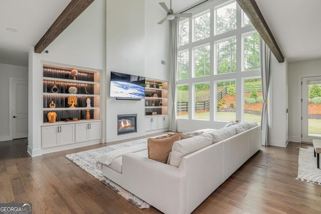 living area with beamed ceiling, high vaulted ceiling, wood finished floors, a fireplace, and a ceiling fan
