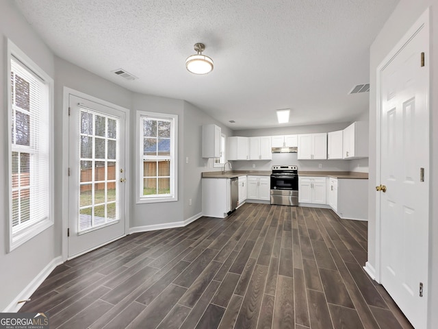 7006 Mahonia Pl, Lithonia, GA 30038 - kitchen featuring appliances with stainless steel finishes, under cabinet range hood, dark wood-style flooring, baseboards, and a textured ceiling
