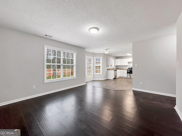 7006 Mahonia Pl, Lithonia, GA 30038 - unfurnished living room featuring baseboards, dark wood-style flooring, and a textured ceiling