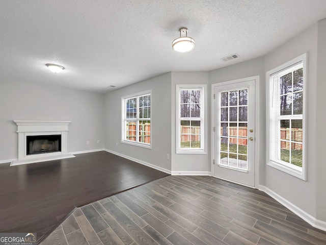 7006 Mahonia Pl, Lithonia, GA 30038 - unfurnished living room with a textured ceiling, dark wood finished floors, baseboards, and a fireplace with raised hearth