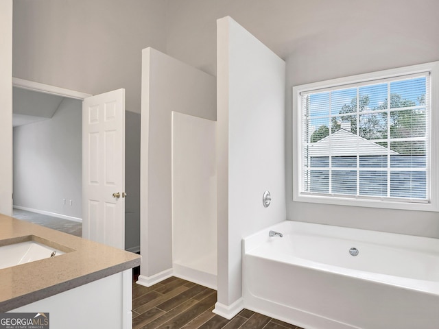 7006 Mahonia Pl, Lithonia, GA 30038 - full bathroom with wood tiled floors, baseboards, a garden tub, a walk in shower, and vanity