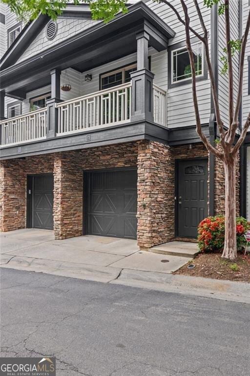 221 Semel Cir NW Unit 273, Atlanta, GA 30309 - view of front of house featuring a balcony, a garage, stone siding, and concrete driveway