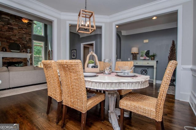 dining room with wood finished floors, crown molding, a chandelier, and a fireplace