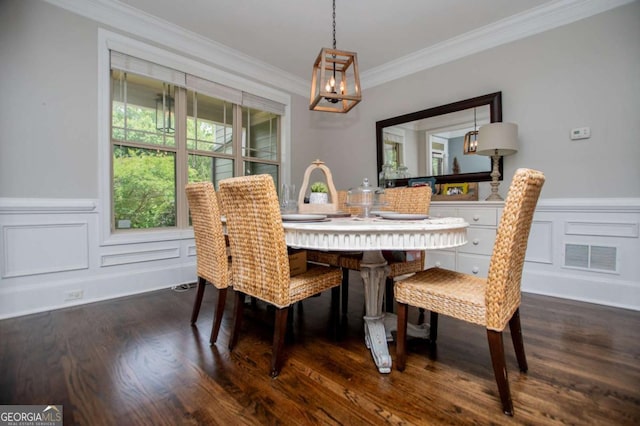dining space with ornamental molding, a chandelier, dark wood-style floors, a decorative wall, and a wainscoted wall