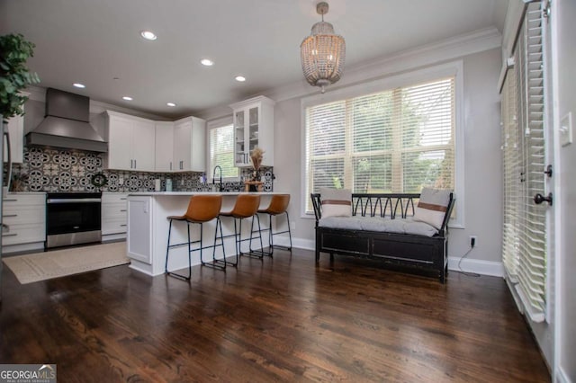 kitchen with custom exhaust hood, stainless steel range with electric cooktop, crown molding, white cabinetry, and decorative backsplash