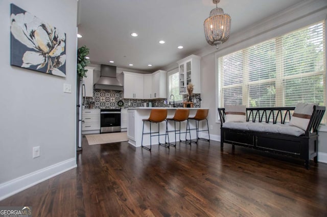 kitchen with custom exhaust hood, stainless steel range with electric stovetop, a peninsula, white cabinets, and a breakfast bar area