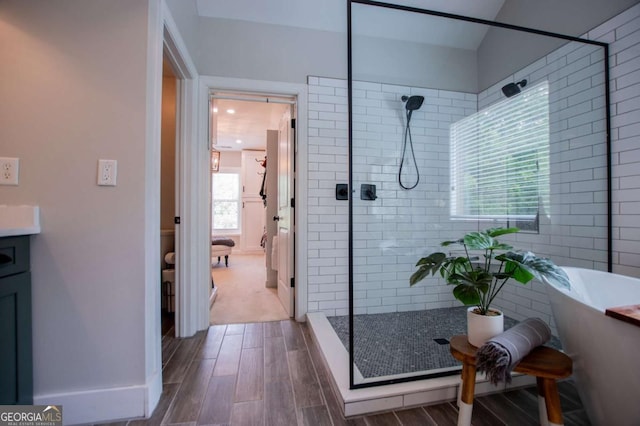 full bath featuring a tile shower, wood finished floors, a soaking tub, and baseboards
