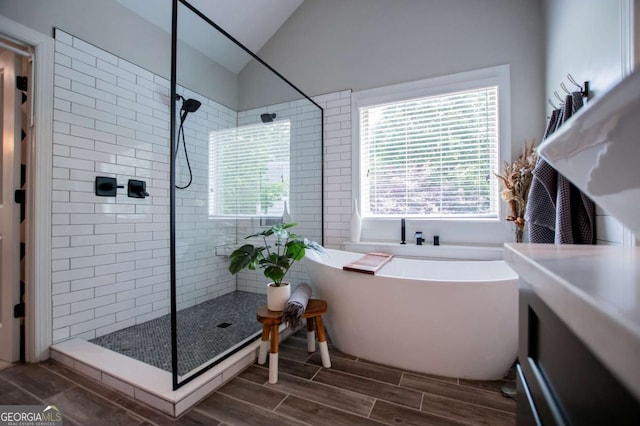 full bathroom featuring a tile shower, lofted ceiling, a freestanding bath, and wood tiled floors