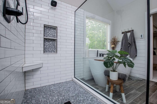 bathroom featuring tiled shower, a freestanding tub, lofted ceiling, and wood finished floors