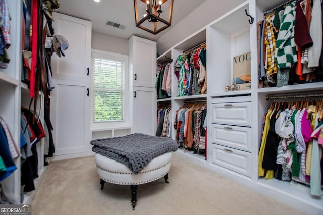 walk in closet featuring a chandelier and light colored carpet