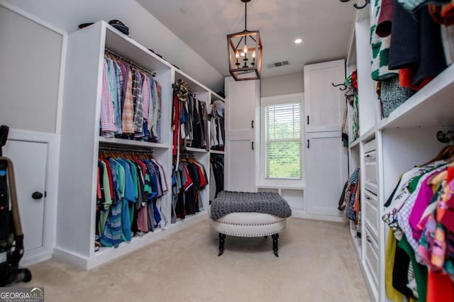 spacious closet featuring a chandelier and light colored carpet