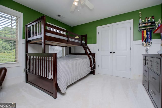 bedroom featuring wainscoting, a ceiling fan, and a closet