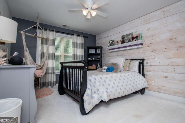 carpeted bedroom with wood walls and a ceiling fan