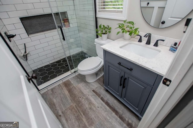 full bathroom with wood finished floors, toilet, a stall shower, and vanity