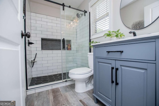full bath with wood finished floors, a stall shower, toilet, and vanity