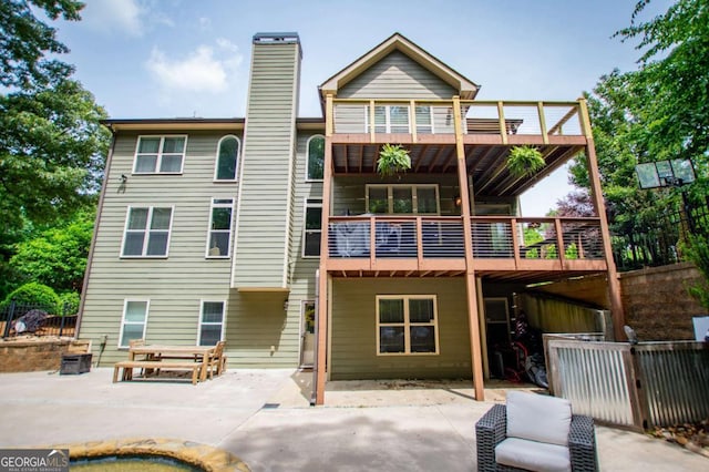 rear view of property featuring a chimney, a patio area, fence, and a wooden deck