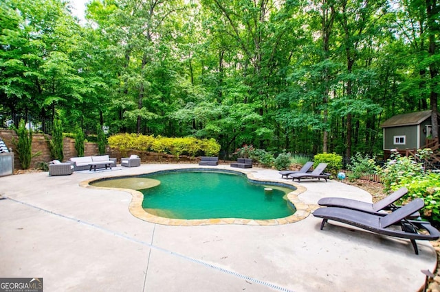 outdoor pool with a patio area, a storage unit, an outbuilding, and fence