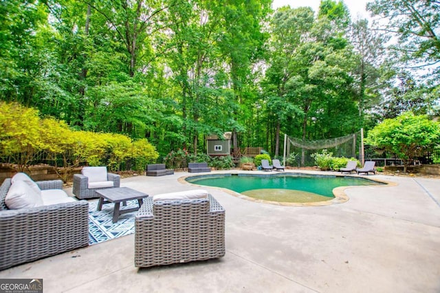 swimming pool featuring a patio area, view of scattered trees, and an outdoor living space
