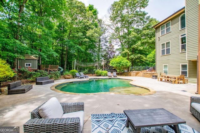 view of pool with a patio, a storage unit, an outbuilding, view of scattered trees, and fence