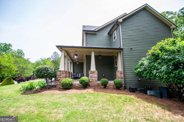 view of front of property featuring covered porch, a front lawn, and stone siding