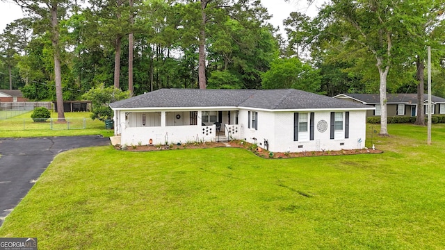 ranch-style house with brick siding, a shingled roof, covered porch, and view of wooded area