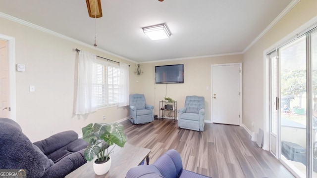 living area with light wood finished floors, crown molding, baseboards, and a ceiling fan