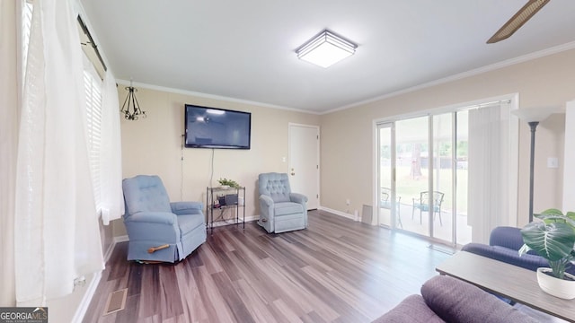living area with wood finished floors, ornamental molding, and baseboards