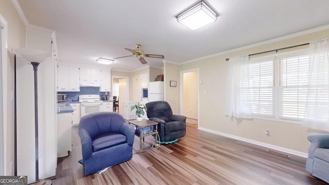living area with light wood-style floors, baseboards, ceiling fan, and crown molding