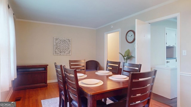 dining space featuring wood finished floors, ornamental molding, and baseboards
