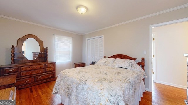 bedroom with wood finished floors, ornamental molding, a closet, and baseboards