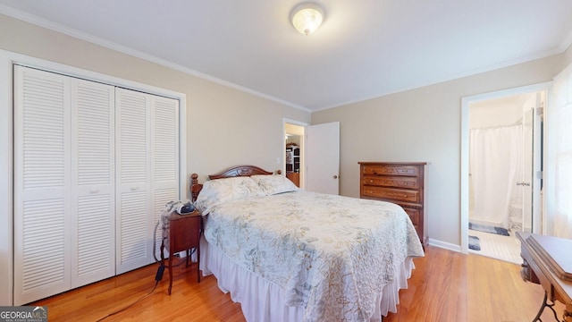 bedroom featuring a closet, light wood finished floors, ornamental molding, baseboards, and ensuite bathroom