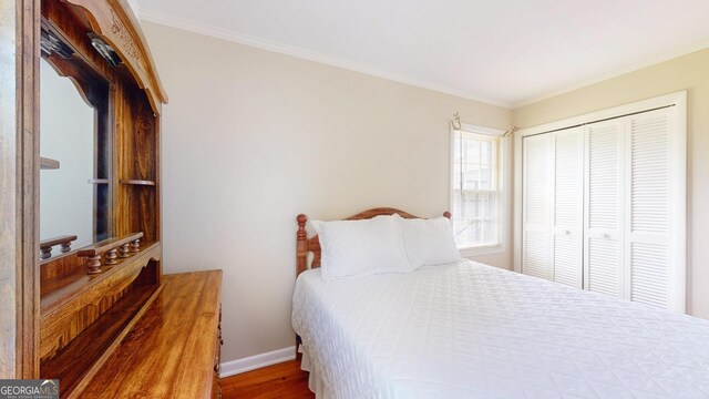 bedroom with baseboards, a closet, crown molding, and wood finished floors