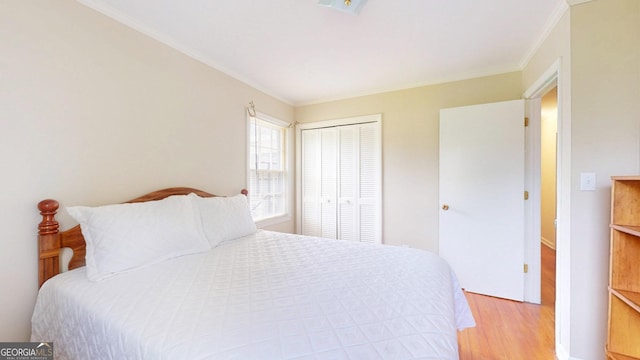 bedroom with light wood-type flooring, ornamental molding, and a closet
