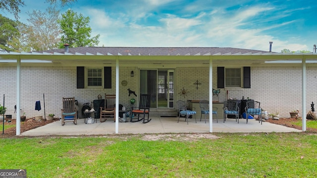 rear view of house with a lawn, brick siding, and a patio
