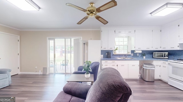 kitchen with stainless steel microwave, white electric range, a ceiling fan, ornamental molding, and white cabinetry