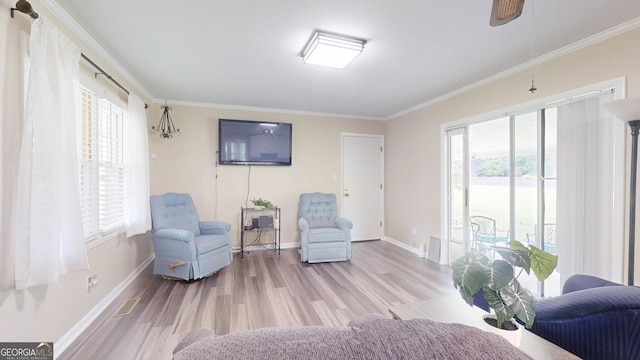 sitting room with wood finished floors, baseboards, ornamental molding, and ceiling fan