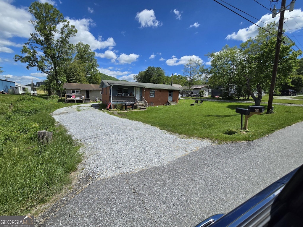 view of front of house featuring gravel driveway and a front lawn