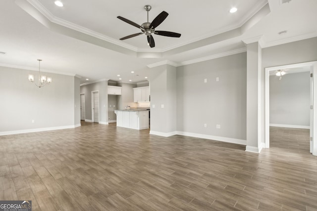 125 The Villas Way, Kingsland, GA 31548 - unfurnished living room featuring a raised ceiling, ceiling fan, a chandelier, wood finished floors, and baseboards